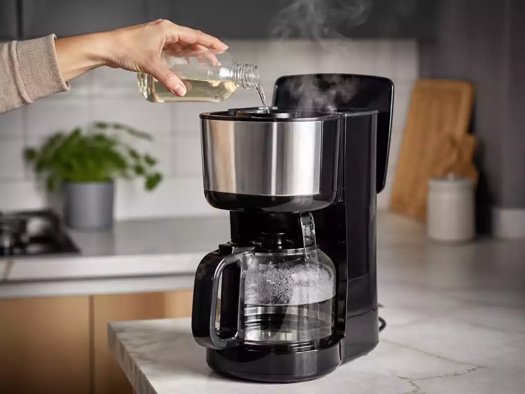 Braun coffee maker being descaled with a descaling solution, with steam gently rising, in a clean kitchen environment
