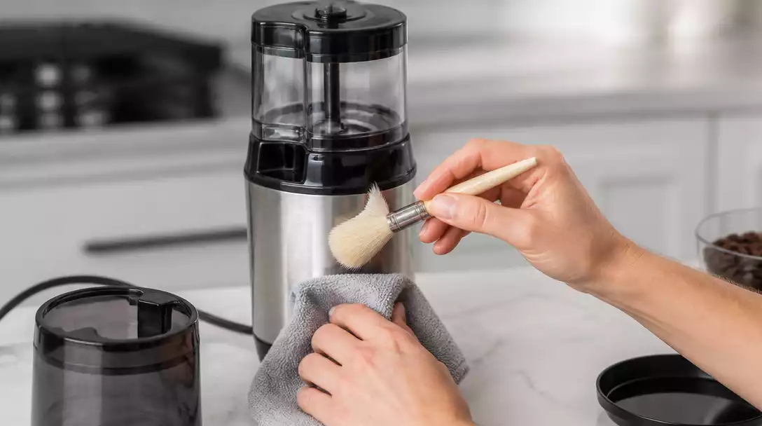 Hamilton Beach coffee grinder being cleaned with a soft brush and damp cloth