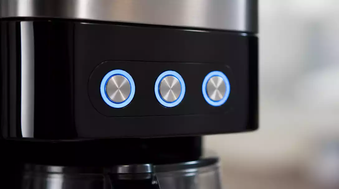 Close-up of a Bella coffee maker's control panel with HOUR, MINUTE, and PROG/PROGRAM buttons highlighted