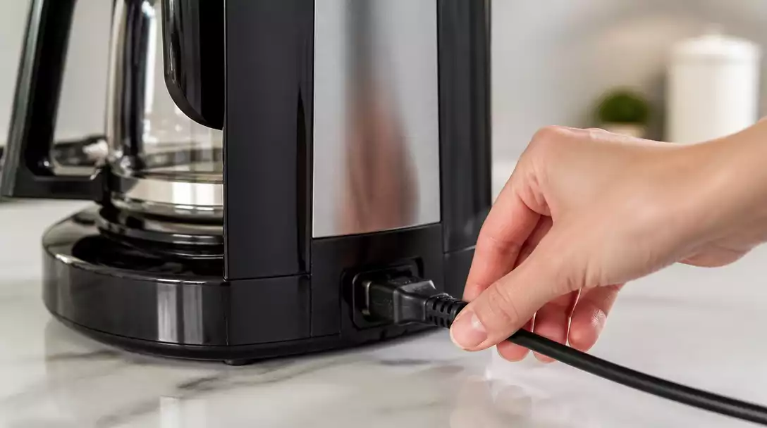 Hamilton Beach coffee maker being inspected for power issues, with a hand checking the power cord