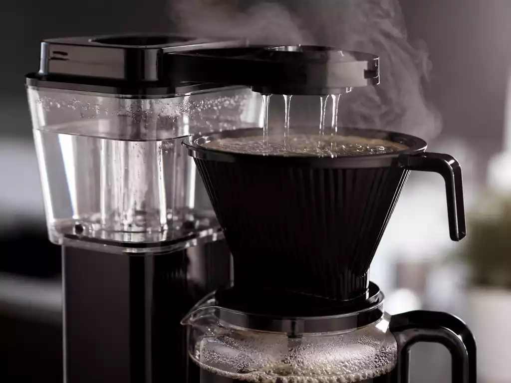 Close-up of a Moccamaster coffee maker brewing, showing consistent water flow and steam, in a modern kitchen setting